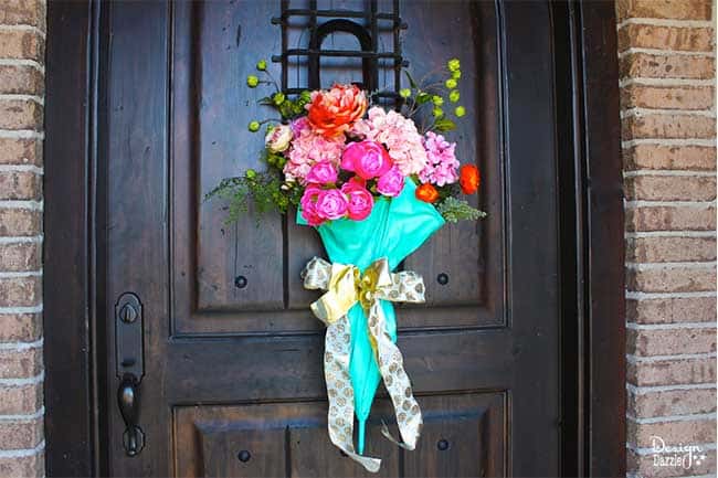 Design Dazzle shows you how to repurpose an old umbrella for some beautiful spring door decor! #diydecor #springdecor