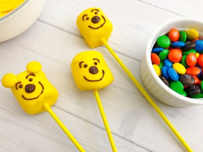 Make these pooh bear marshmallow pops in minutes! So easy and quick to make and super fun too! The kids will definitely enjoy making AND munching on them! - Design Dazzle