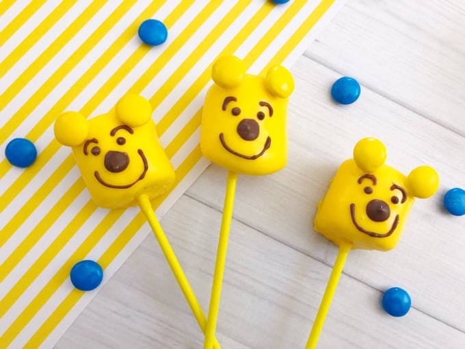 Make these pooh bear marshmallow pops in minutes! So easy and quick to make and super fun too! The kids will definitely enjoy making AND munching on them! - Design Dazzle